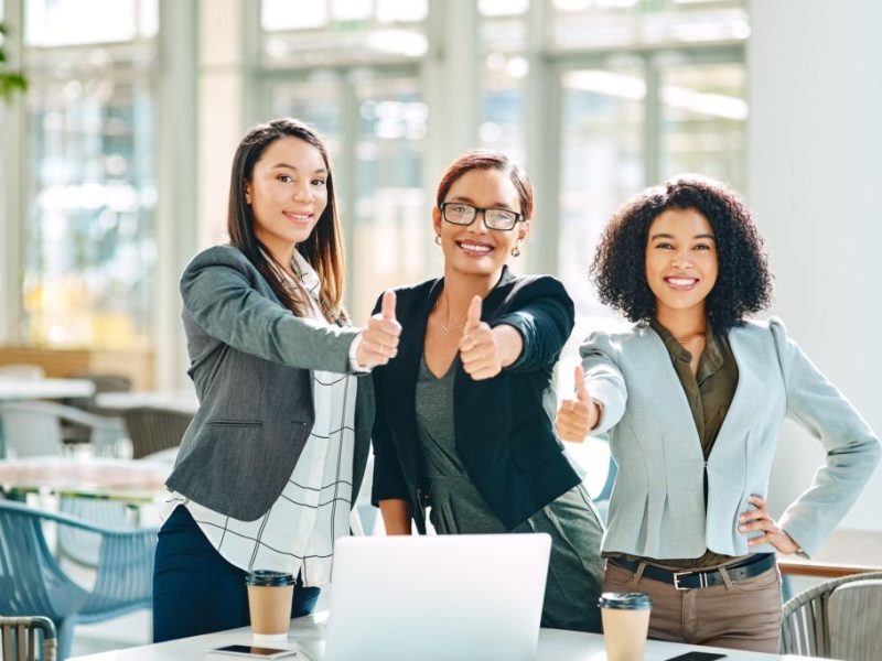 Cropped shot of young businesswomen showing thumbs up while having a meeting in the convention centre